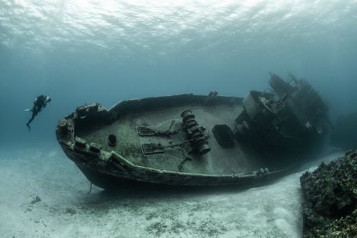 Scuba divers examining the famous USS Kittiwake submarine wreck in the Grand Cayman Islands
