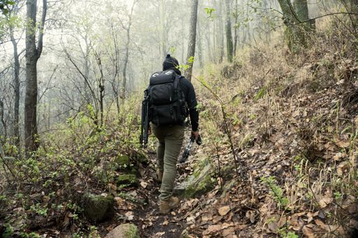 A male with a backpack hiking and climbing to the top of El Pinal volcanic mountain in Puebla, Mexico