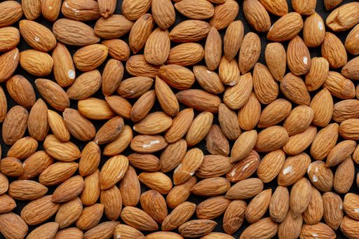 A wooden bowl filled with a variety of nuts with white salt on their brown skin