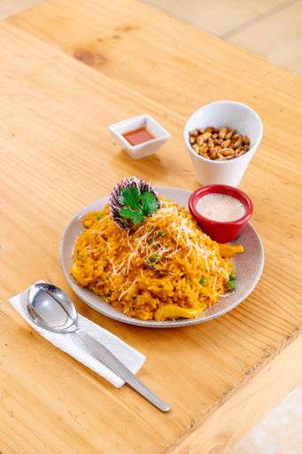 Two ceramic bowls containing steaming food and a pair of metal forks, placed on a natural wooden table surface