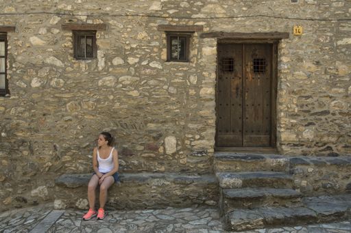 young girl sitting in a village with stone houses and cobblestones