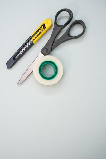 A closeup shot of scissors adhesive tape and a utility knife