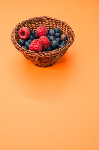 A closeup shot of blueberries and raspberries in a basket