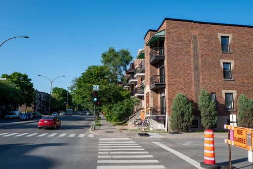 Two bright yellow construction cones are placed at the entrance of a street to indicate that the area is closed off to traffic