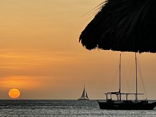 A closeup view of ships sailing in the sea under a sunset sky