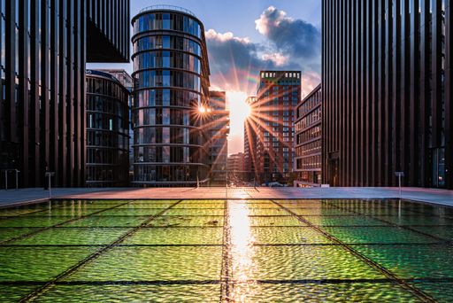 Sunlight filters through tall city buildings