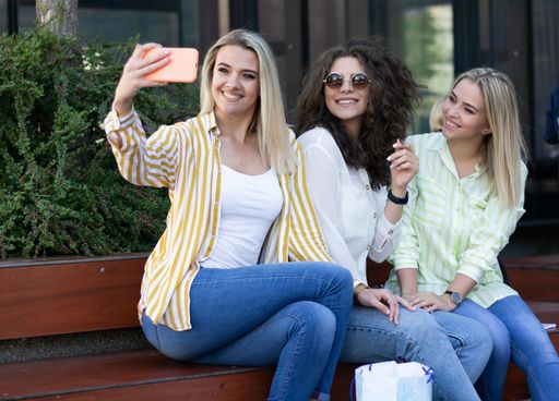 Three happy friends taking a selfie outdoors