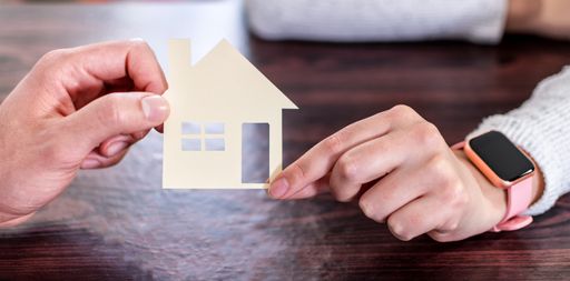 A closeup shot of the couple hands holding paper house - real estate and family concept