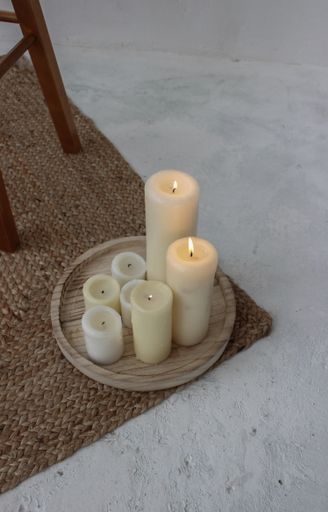 A vertical shot of a tray with thick candles on the floor