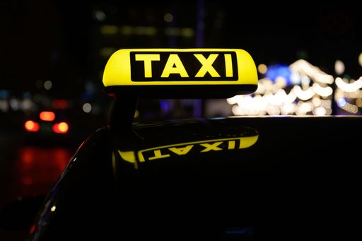 A yellow taxi sign illuminated by the daylight, mounted on the back of a vehicle, ready to provide transport services