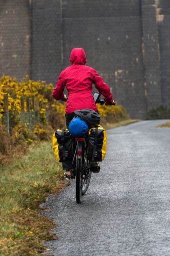 A vertical, close-up shot of a woman cycling on the road near  Ben Crom Reservoir, North Ireland