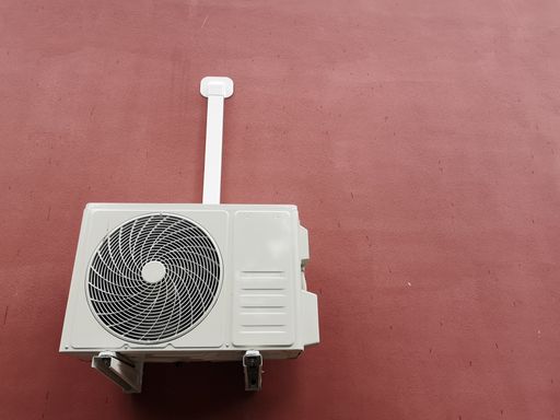 A closeup shot of a white air conditioner hanging on the outside wall