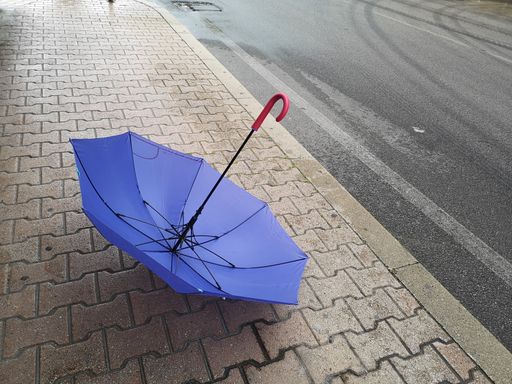 A closeup shot of a blue opened umbrella abandoned on the street