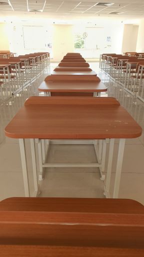 The wooden decks and chairs arranged in the empty classroom