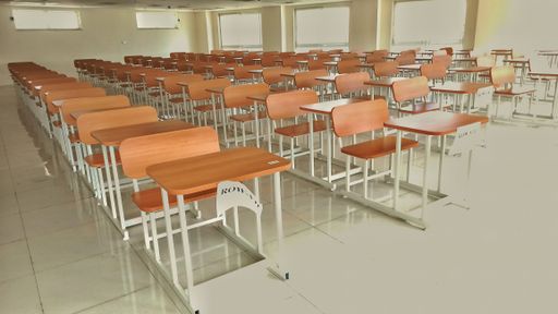 The wooden decks and chairs arranged in the empty classroom