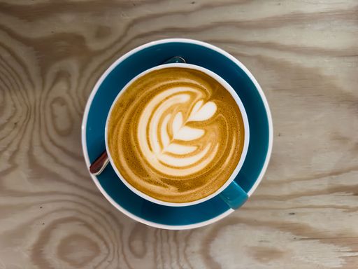 A top view of a steaming cup of hot coffee on a wooden table