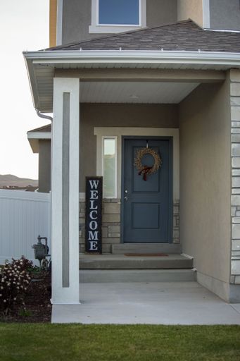 A shot of the house entrance, the white door with Christmas decoration, and the sign saying Welcome.