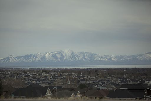 A shot of a gloomy city and mountains fully covered with snow in the background.