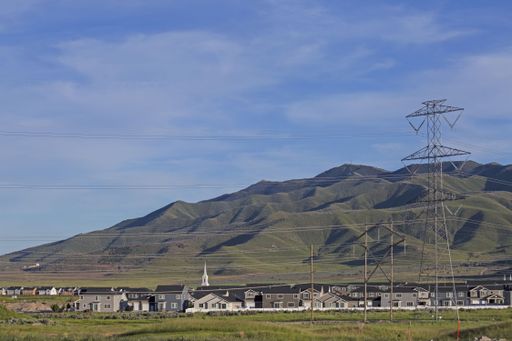 A shot of the houses next to each other in the background of green hills.
