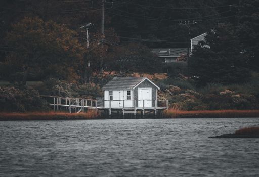 A picturesque view of a tranquil lake with a boat house in the foreground and majestic mountains in the background