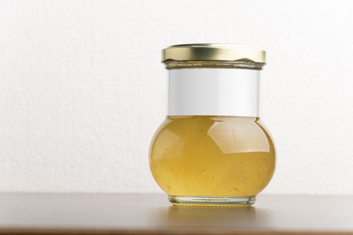 A citron jam in a glass jar with a round cap on the table, editable mock-up series template ready for design, label selection path included