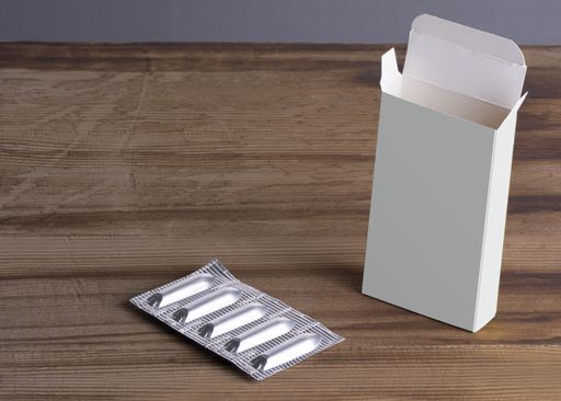 A suppositories loaf and empty box on a wooden table, mockup template ready for design, selection path included