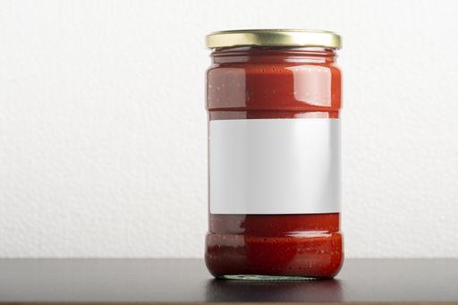 A tomato paste glassy jar with a round cap on the table, editable mock-up series template ready for design, label selection path included