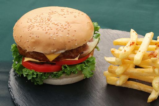 A delicious hamburger with melted cheese, juicy tomatoes, and crispy golden French fries.