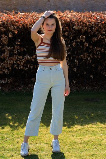 A vertical shot of a young caucasian girl posing in the garden on a sunny day
