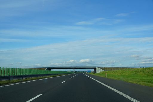A closeup shot of an empty highway and a bridge under the blue sky