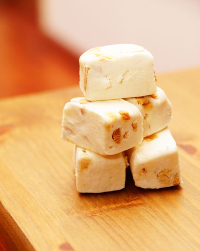 A vertical shot of soft nougat with peanuts and fruits in a wooden table