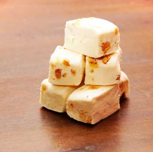 A closeup shot of soft nougat with peanuts and fruits in a wooden table