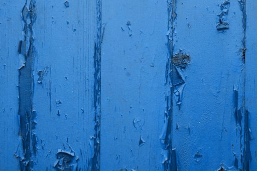 A closeup shot of a blue weathered wooden wall with peeling paint