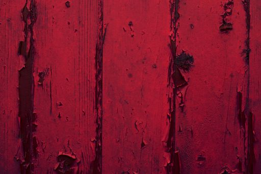 A closeup shot of a red weathered wooden wall with peeling paint