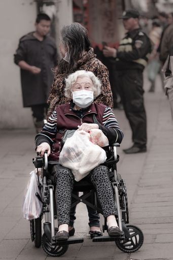 An Asian old woman sitting in a wheelchair on the streets of Suzhou, China.