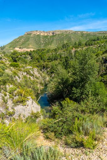 A vertical shot of hills covered in greenery on the Route of Pantaneros under the sunlight in Chulilla, Spain