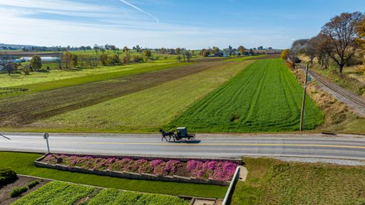 An Aerial View of an Amish Pick Up Horse and Buggy Traveling Down a Rural Country Road, Thru Farm Fields on a Sunny Autumn Day