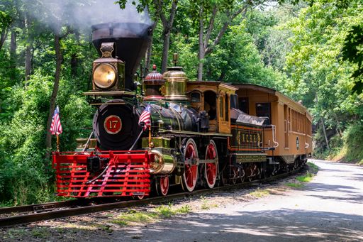 A vintage steam locomotive engine driving on a railway on a sunny day