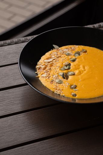 A vertical shot of the pumpkin cream soup with different nuts on the half of it.