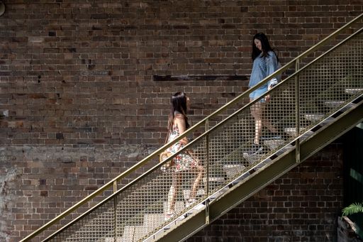 Trendy woman walk on the metal stairs of a courtyard building.