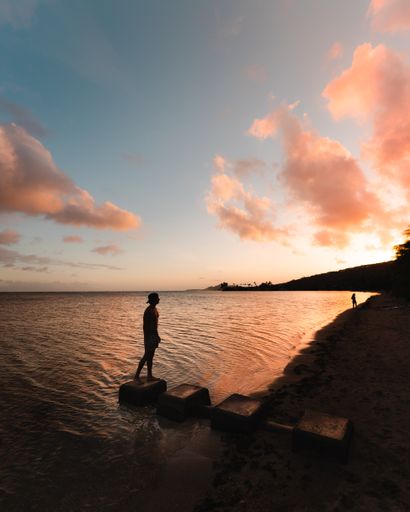 A silhouette of a person on a sandy seashore observing the beautiful sunset over Hawaii Kai