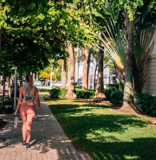 A beautiful shot of a girl from behind walking in a park full of trees wearing sportswear