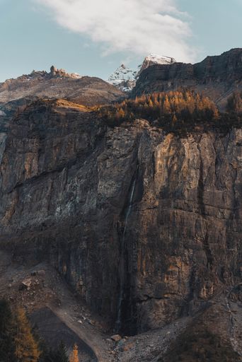 A scenic view of a waterfall cascading down a rocky mountain face in the Alps