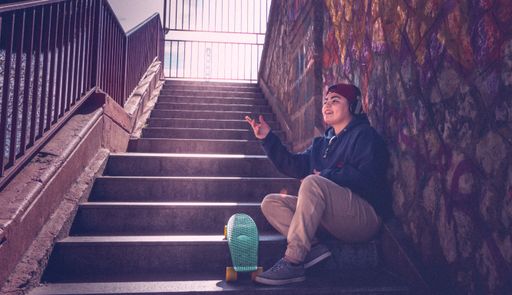 A closeup shot of a cool Hispanic skater having a rest on stairs in the street