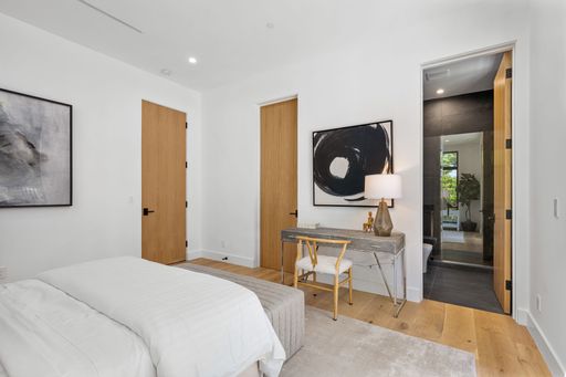 A cozy bedroom interior featuring a single bed and a dresser, with a large window providing natural light