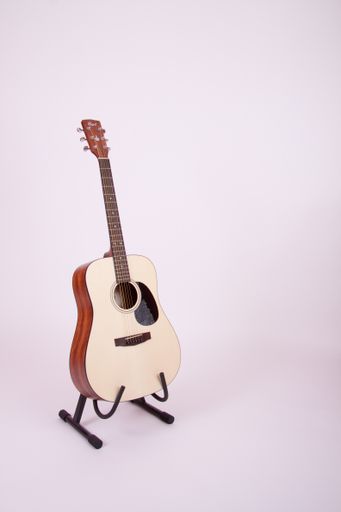 A vertical shot of a guitar on the stand in a white background