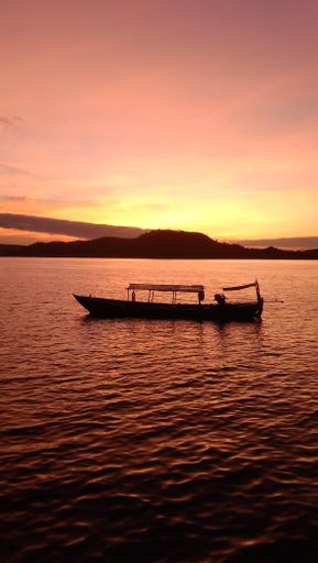 A vertical shot of a fishing boat on a sunrise sky background in Cambodia