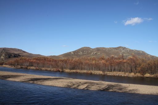 A scenic view of a river flowing through a barren landscape on a sunny day