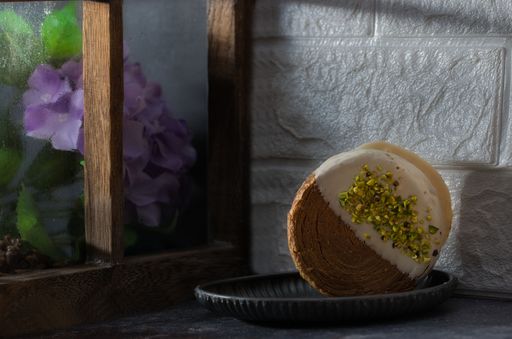 A delicious Croissant roll resting on a black tray, illuminated by natural light from the window
