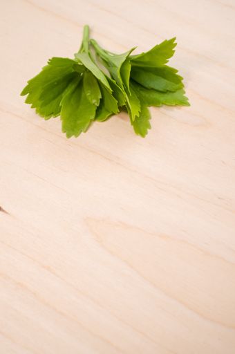 A vertical shot of fresh red clover leaves on a wicker basket on a wooden surface